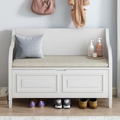 a white bench with some shoes on it and a coat rack hanging above the bench