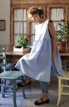 a woman standing in front of a table wearing a blue and white striped apron dress