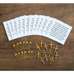 several crosses, pins and paper clips are laid out on a wooden table next to a book