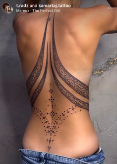 the back of a woman's body with tattoos on her stomach and an intricate design