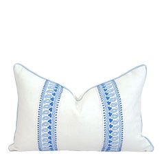 a blue and white pillow with an embroidered border on the front, sitting against a white background