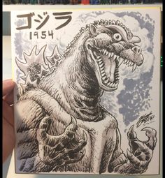 a hand holding up a card with an image of a godzilla