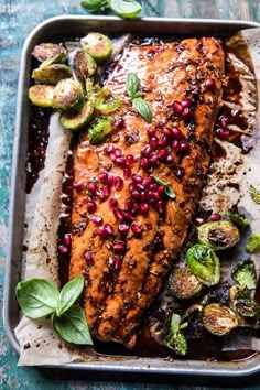 salmon with pomegranates and brussel sprouts on a baking sheet