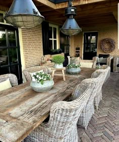 an outdoor dining table with wicker chairs and potted plants on the outside patio