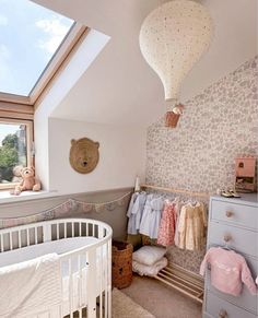 a baby's room with a crib, dresser and teddy bear on the wall