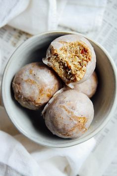 four doughnuts in a bowl on top of a white napkin with a bite taken out