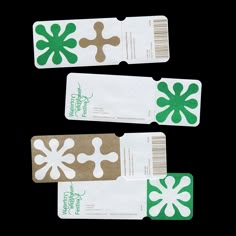 three tags with green and white designs on them are sitting next to each other in front of a black background