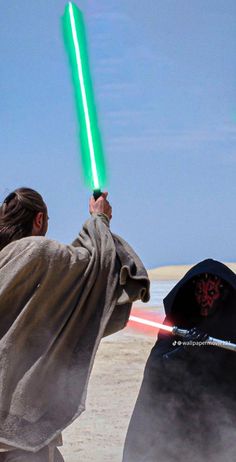 two people with lightsabens on their backs in front of a blue sky and some sand