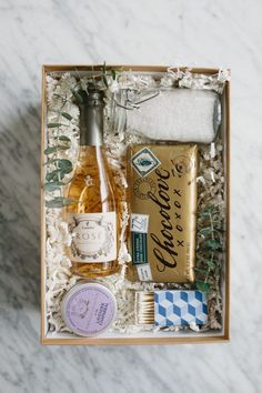 an open box containing two bottles of wine and some other items on a marble surface