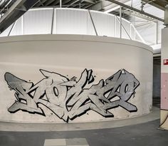 graffiti is painted on the side of a large tank in an industrial area with white walls