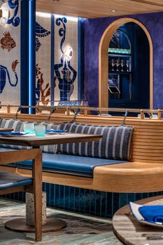 the interior of a restaurant with wooden benches and blue tile on the wall behind it