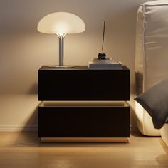 a night stand with a lamp on it next to a bed