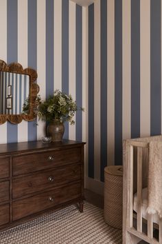 a dresser and mirror in a room with striped walls