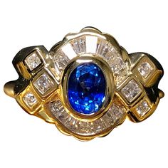 A gorgeous ring done in supple 18K yellow gold and centered with a gorgeous royal blue natural bezel set sapphire weighing approximately .80ct surrounded by approximately 1.60cttw in tapered and square baguette as well as round diamonds. Dimensions/Weight: Rings measures .60” by .75” and weighs 8.3g. Size 6.5 (sizable). Condition: All stones are secure and in perfectly wearable condition. R-S Baguette Diamond Ring, Baguette Diamond Rings, Gem Stone, Baguette Diamond, Cluster Ring, Bezel Setting, Cocktail Rings, Round Diamonds, Royal Blue