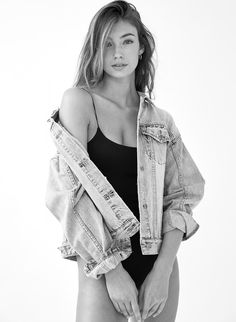 a black and white photo of a woman in a bathing suit wearing a jean jacket