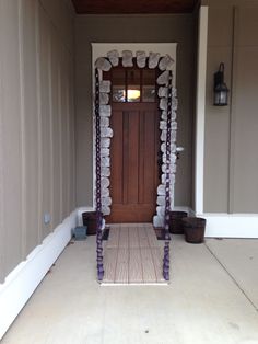 the front door is decorated with purple ribbons and white vases, along with two planters on either side