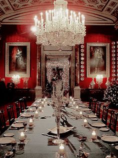 a long dining table is set with place settings and candles in front of the chandelier