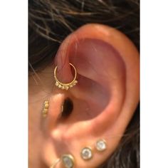 a close up of a person's ear with gold piercings