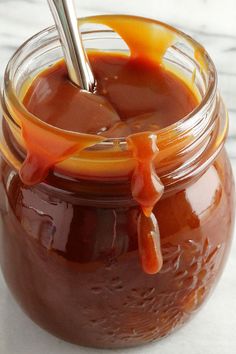 a spoon in a jar filled with caramel sauce