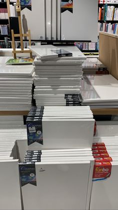 many books are stacked on top of each other in a store aisle with shelves full of books