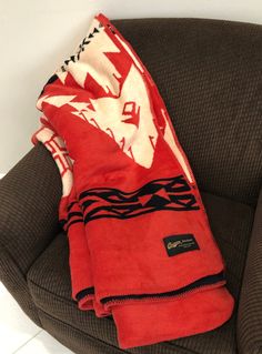 a red and white blanket sitting on top of a brown chair