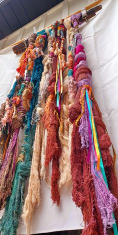 there are many different colored yarns hanging on the wall