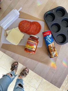 a person standing next to some food on top of a wooden table with muffin tins