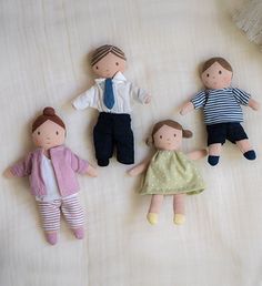 four dolls laying on top of a bed next to each other in different outfits and clothes