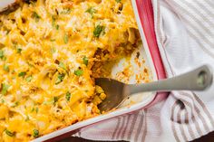 a casserole dish with chicken, cheese and parsley in it on a striped cloth