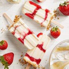 three popsicles with strawberries and whipped cream on them, next to two bowls of yogurt