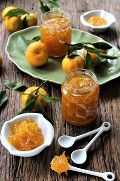 some oranges are sitting on a table with spoons and jars filled with them