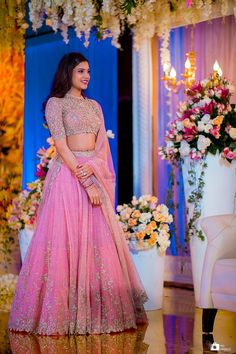 a woman in a pink lehenga standing next to flowers