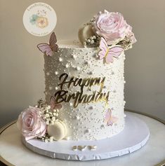 a white birthday cake decorated with pink flowers and butterflies