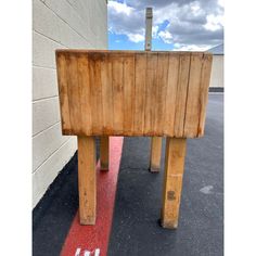 a wooden bench sitting on top of a parking lot next to a wall and red line