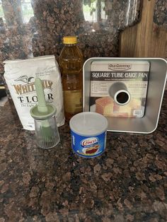 ingredients for cake sitting on top of a counter next to a bottle of liquid and tin