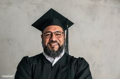 a man with glasses and a beard wearing a graduation cap, gown and tassel