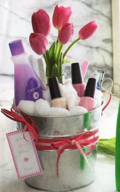 pink tulips are in a silver bucket with soap and lotion on the counter