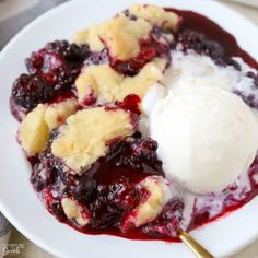 a white plate topped with blueberry cobbler and ice cream on top of it