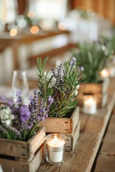 candles and flowers in wooden containers on a table