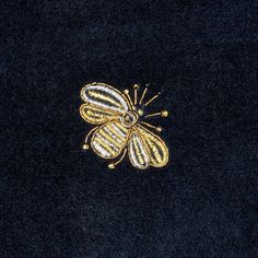 a gold and black flower brooch sitting on top of a black cloth covered in sequins