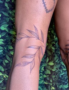 a close up of a person with tattoos on their legs and arms, standing in front of bushes