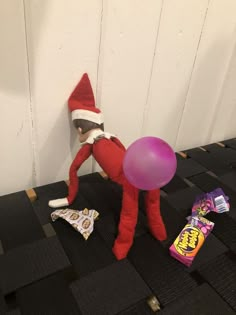 an elf laying on the floor with candy and balloons