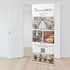 a white banner stands in front of an open door on a wooden floor with flowers and greenery