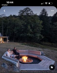 two people sitting around a fire pit in front of a house