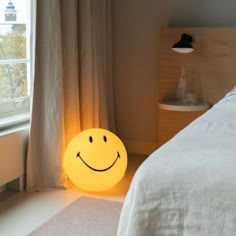 a smiley face lamp sitting on the floor next to a bed