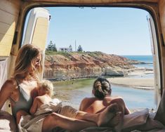 two women and a child are sitting in the back of a truck looking out at the ocean