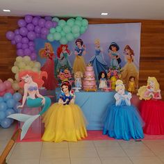 there are many princesses on the table at this birthday party with balloons in the background