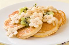 pancakes with bananas, kiwis and other toppings on a white plate