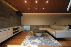 a modern living room with white furniture and wood ceilinging on the walls is lit by recessed lights