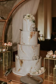 a three tiered wedding cake sitting on top of a table next to a knife and fork